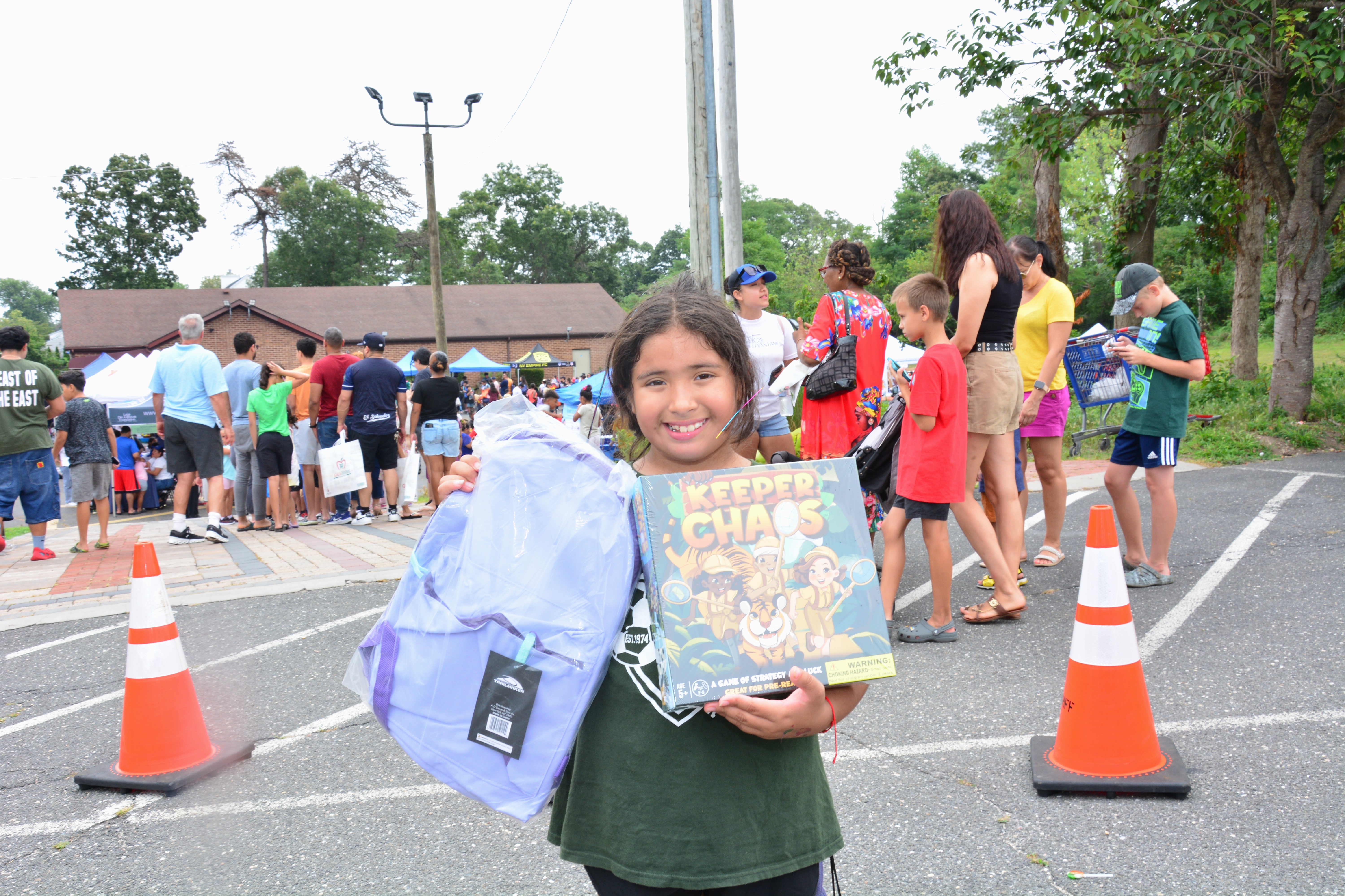A child hold a new backpack and book at a school supply distribution event held on Aug. 16, 2025 in Brentwood.