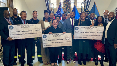 Group of people holding three checks.