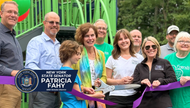 Senator Fahy, Town Supervisor David VanLuven, and residents cut ribbon on the new playground in background