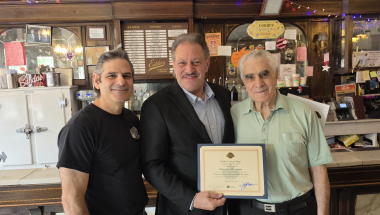 Senator Addabbo presents a Historic Business Registry certificate to Vito Citrano, left, and his father Giuseppe (Joe) Citrano, the co-owners of Eddie's Sweet Shop.