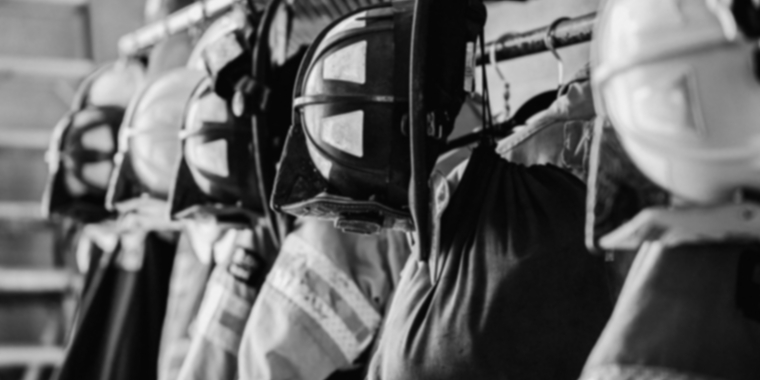 Photo of firefighter helmets and jackets hanging in a station house.