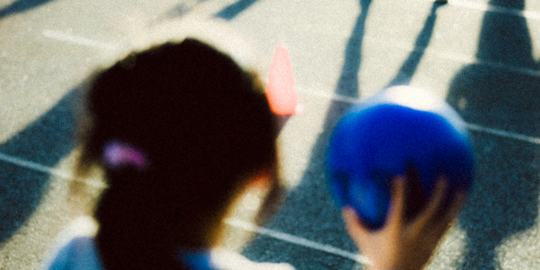 Photo of a child playing with a ball playing with other children who are out of frame.