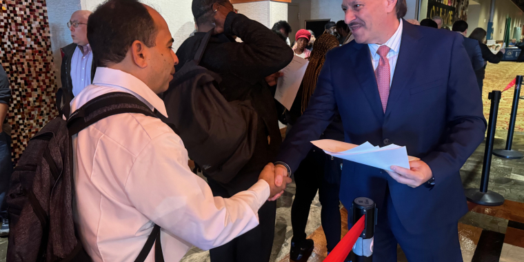 Senator Addabbo greets jobseekers and gives them a list of employers present at the fair.