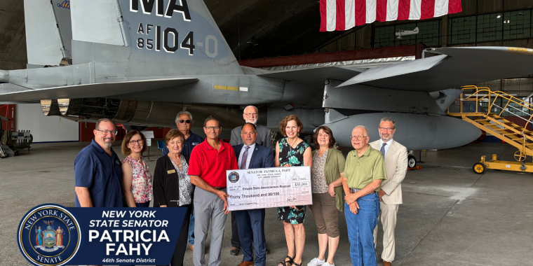 Senator Fahy and ESAM representatives in front of a F-15C fighter jet with large check
