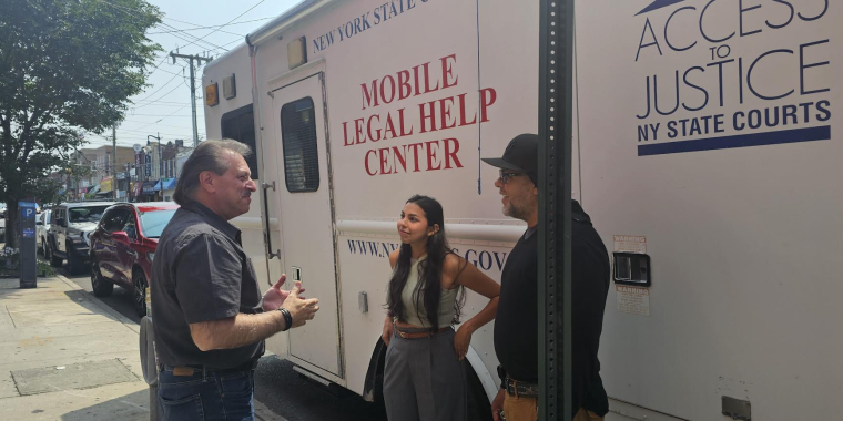 Senator Addabbo greets Daniela López the Mobile Legal Help Center Coordinating Paralegal and Elliot Medina the Driver of the Mobile Legal Help Center.