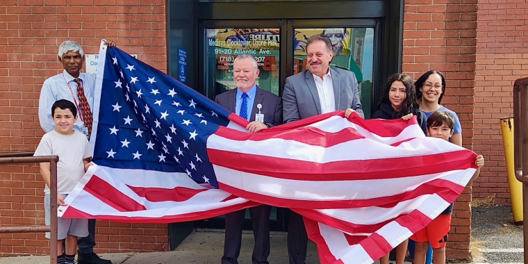 Senator Addabbo presents flag to Patrick Rudden, manager at Jamaica Hospital and his wife and children.